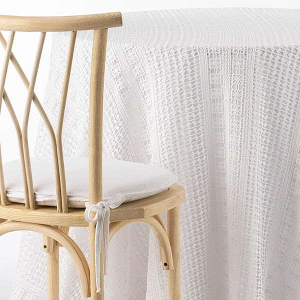 A chair next to a table with Bohemian White Crochet fabric