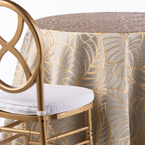 A chair next to the table with Amazon Gold Leaf silver table linen