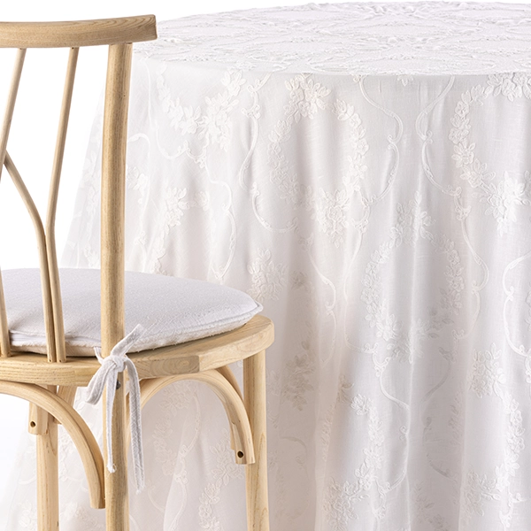 A chair next to the table with Kelly White Floral tablecloth rental