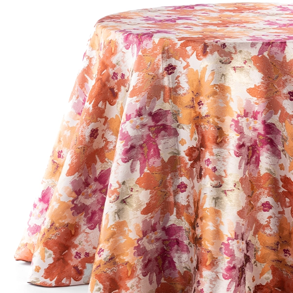 A round table covered in Penelope Pomegranate fabric, available for event linen rental.