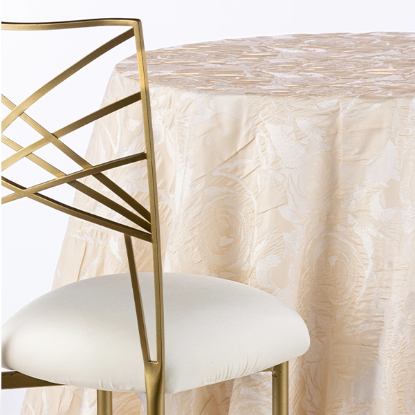 A chair next to the table with Rosie Champagne beige tablecloth rental