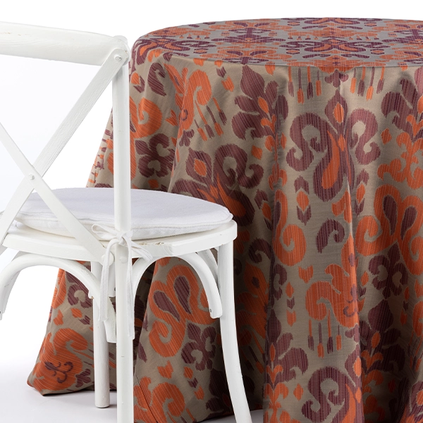 A chair next to the table with Sutra Beet purple orange patterned table linen