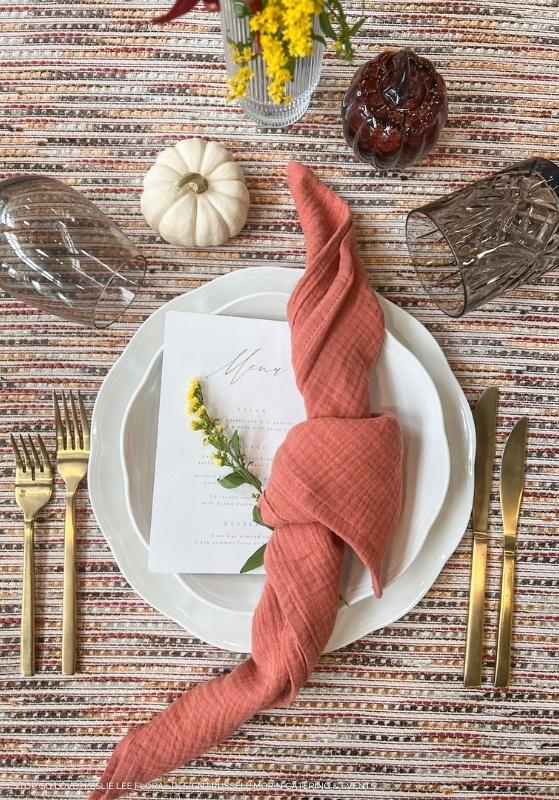 An elegant table setting with a napkin and a table linen rental on it.