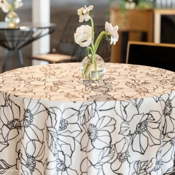 A table with an Archie Black tablecloth and flowers in a vase.