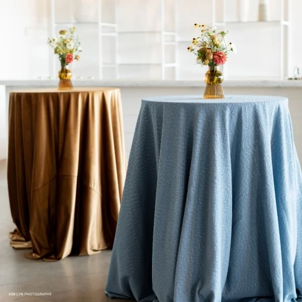 A table with a Velvet Hazel vase of flowers on it, perfect for an elegant event linen rental.