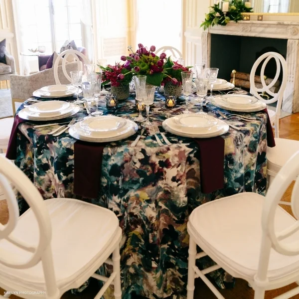 A beautifully arranged table set for a dinner party, featuring Bouquet Lapis event linen rental. The elegant Bouquet Lapis linen rental completes the sophisticated ambiance, adding a touch of refined luxury to every place setting.