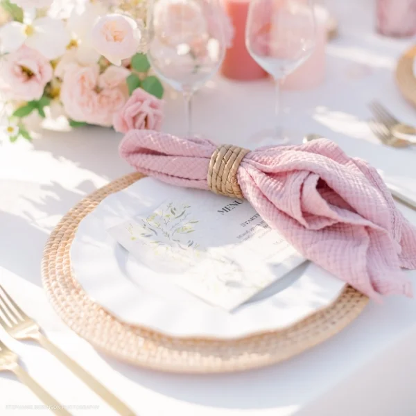 An elegantly dressed table set with a Callie Dusty Rose Napkin and plates, available for event linen rental.