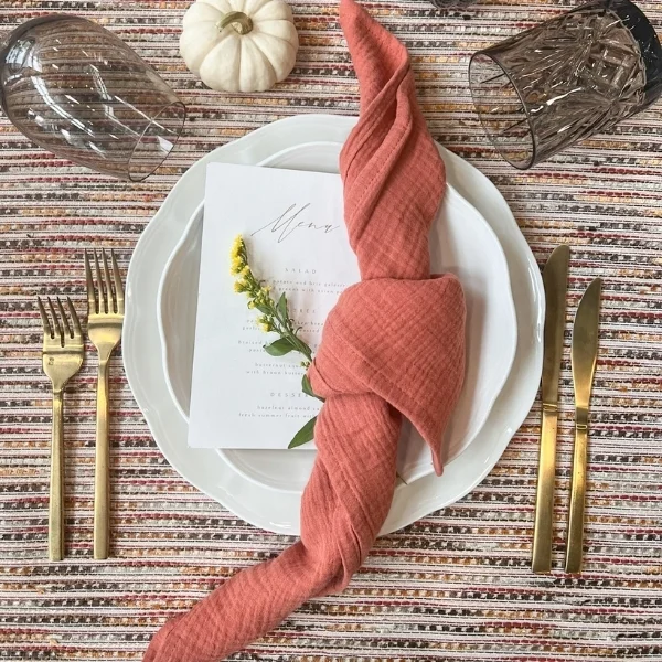 A table setting with a Canyon Rust napkin and a napkin on it available for event linen rental.