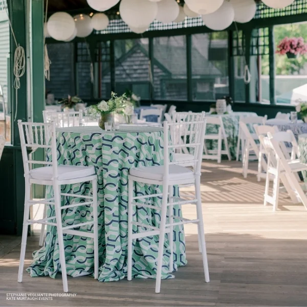 An elegant wedding reception with white chairs and Harlow Keylime tablecloths available for event linen rental.