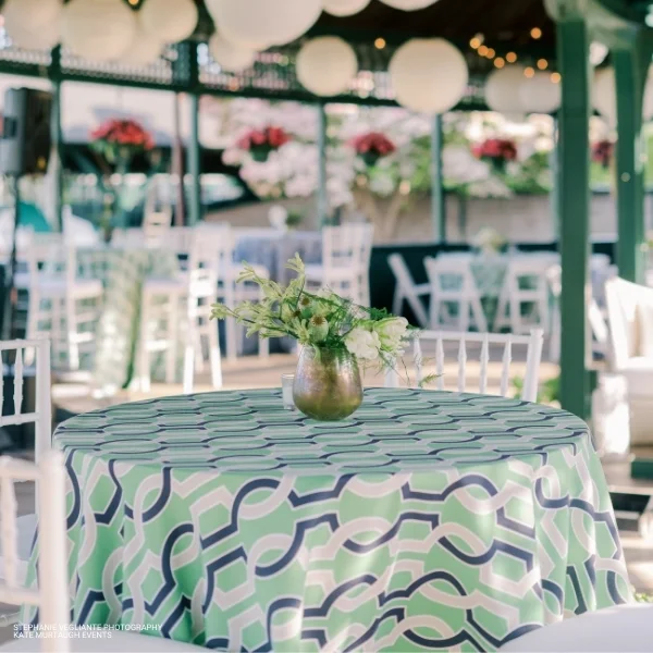 An event Harlow Keylime linen rental table with green and white tablecloths and chairs.