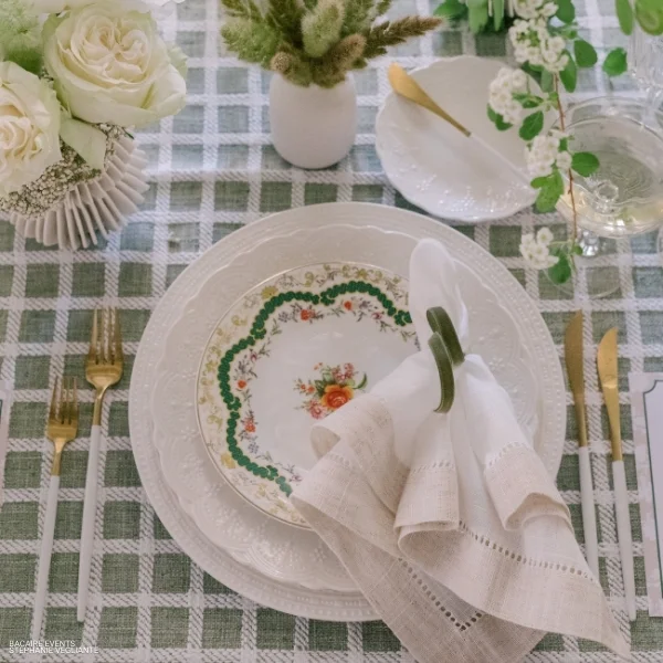 A table setting with green and white plates, decorated with Hemstitch White & Flax Napkin rental.