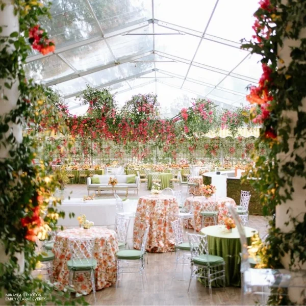 A wedding reception in a tent with Layla Floral rental and flowers hanging from the ceiling.