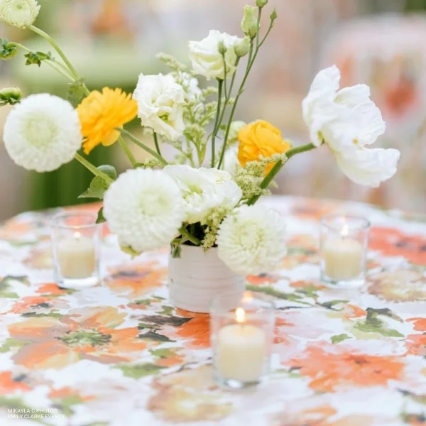 An orange and white Layla Floral arrangement on a tablecloth, perfect for event linen rental.