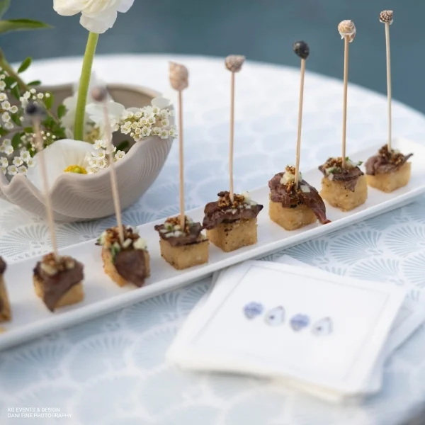 A plate of appetizers on a table with Lennon Powdered Blue linen rental, adorned with flowers.