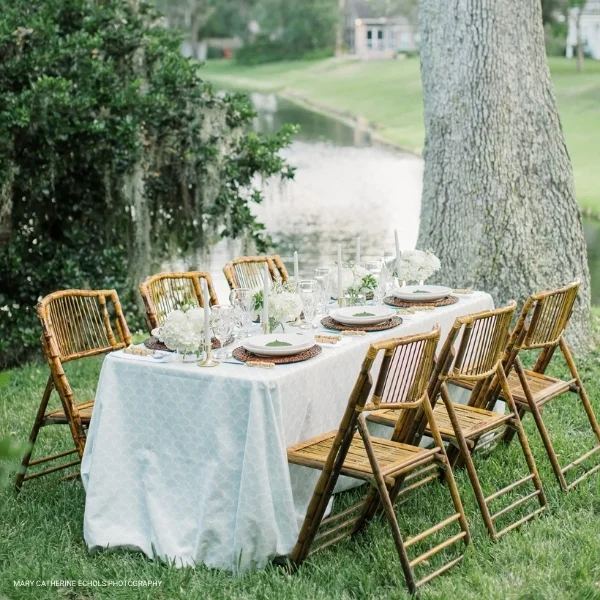 A Lennon Powdered Blue set up in the grass near a pond, available for event or table linen rental.