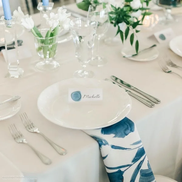 A table setting with blue and white Livia Sapphire Napkin place settings available for event linen rental.