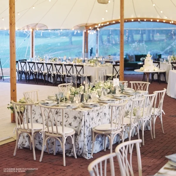 A tent with tables and chairs set up for an event, featuring Magnolia Fog table linen rental services.
