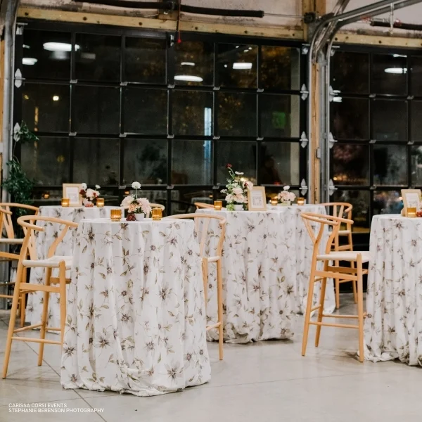 A wedding reception in a warehouse with tables and chairs available for Magnolia Fog linen rental.