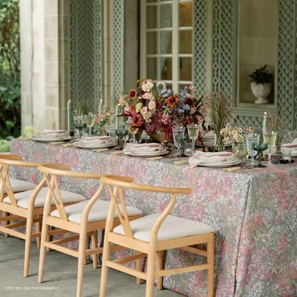 A Mariposa Garden set with chairs and a floral tablecloth available for event linen rental.