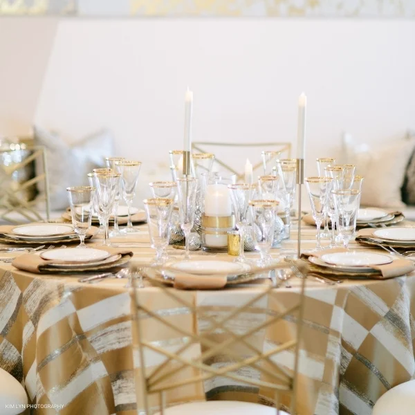 A table setting with Metropolitan Gold and white tablecloths available for event linen rental.