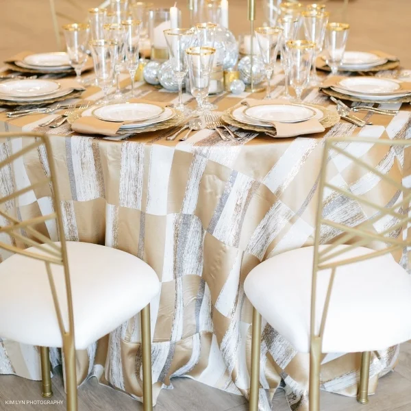 A glamorous table setting with elegant white chairs and luxurious Metropolitan Gold accents.