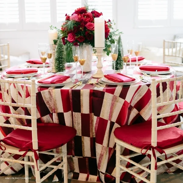 An elegant Christmas table setting featuring the Metropolitan Red tablecloth, available for table linen rental.