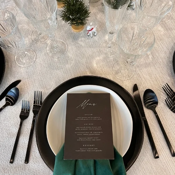An elegant table setting with Mila Woven White linens, silverware, and napkins available for event linen rental.