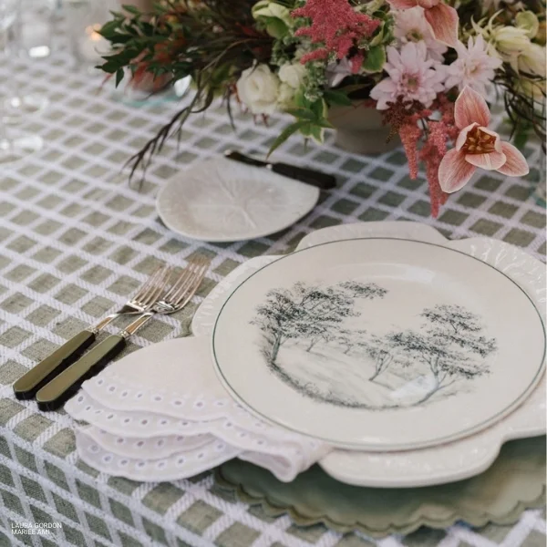 A table with beautifully decorated Sadie Scalloped Cream Napkins and flowers for your special event and party. Ideal for event linen rental or table linen rental services.