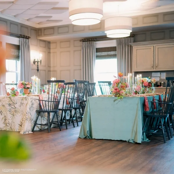 A room with tables and chairs available for Velvet Peacock linen rental.