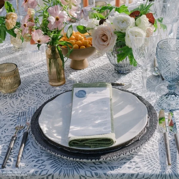 A table setting with plates, silverware, and flowers available for Sophia Lace rental.