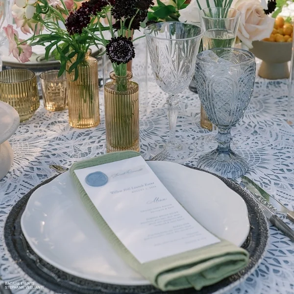 A table setting with elegant place settings and beautiful flowers, complemented by Callie Sage Napkin rental.
