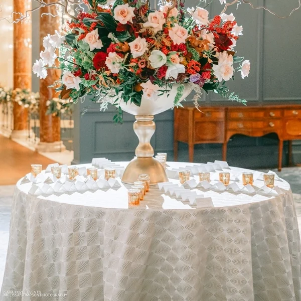 A table with a white tablecloth rented from an event linen rental company, adorned with a Stella Champagne.