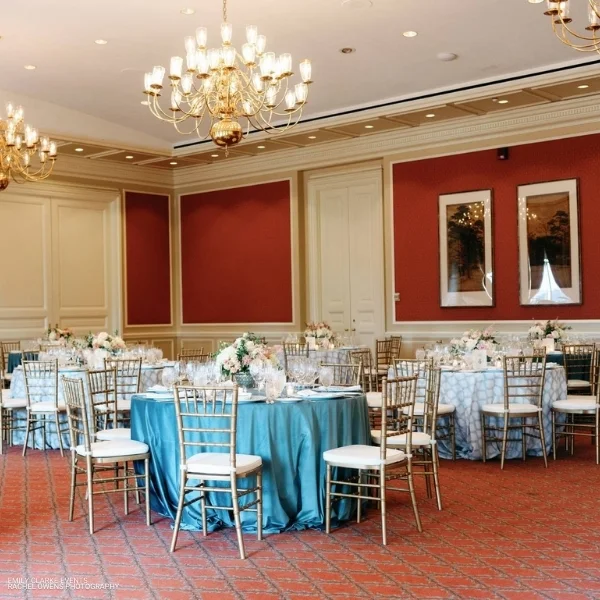 A room with Lexington Seafoam tables and chairs set up for a wedding reception, featuring elegant table linen rentals.