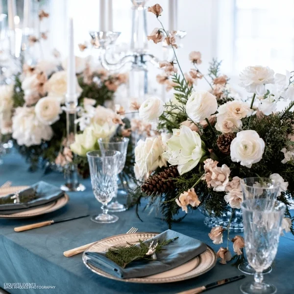 A blue table setting with white flowers and candles, perfect for an elegant event. With our Velvet Deep Sea Napkin rental services, you can enhance any occasion by adding a touch of luxury and sophistication to your.