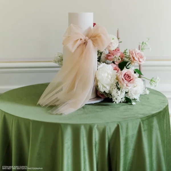 A Velvet Evergreen on a green table with a bow available for event linen rental.