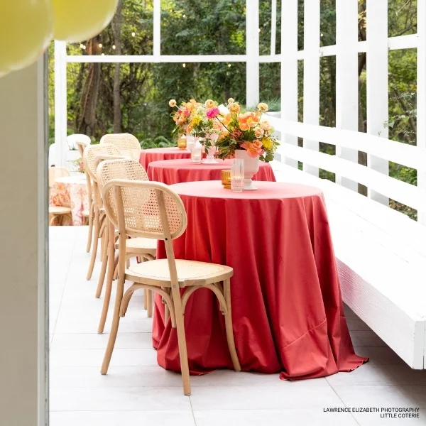 A porch featuring a Velvet Orange Rose with a red tablecloth and chairs.