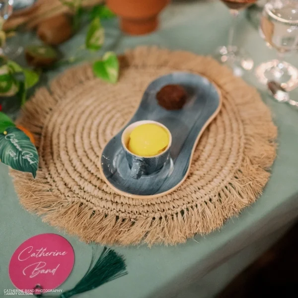 A place setting with a Velvet Peacock plate and flowers on it available for table linen rental.