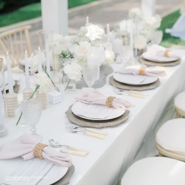 A white table setting with pink and white plates and Velvet Blush Napkins available for table linen rental.