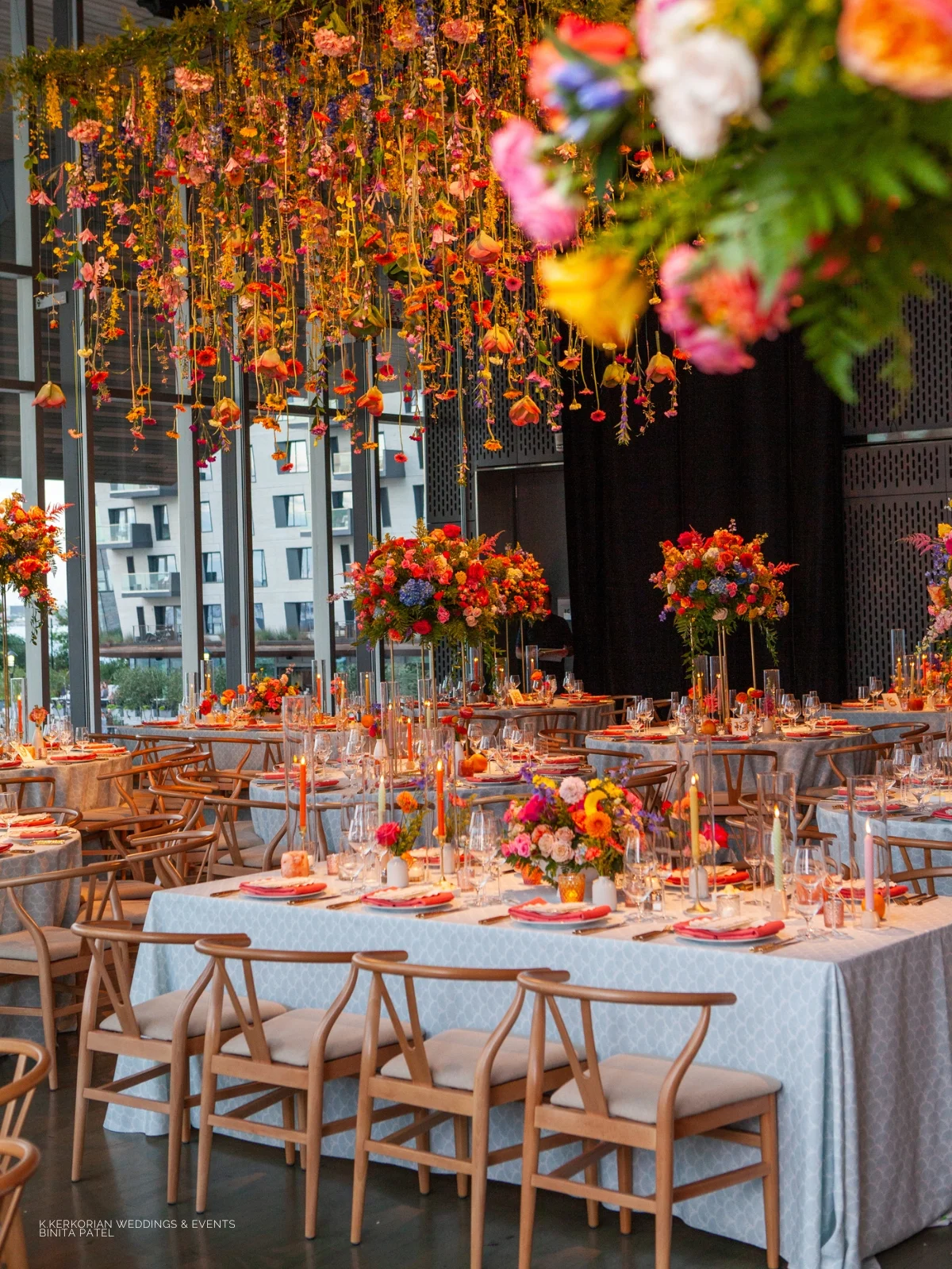 An event linen rental featuring a wedding reception set up with colorful flowers hanging from the ceiling.