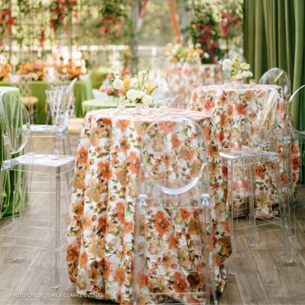 A table set up with vibrant orange and green floral tablecloths, perfect for an event requiring table linen rental.