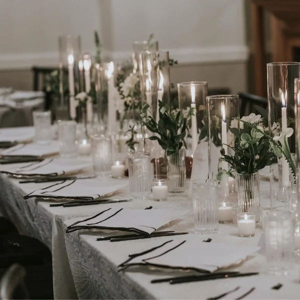 A beautifully set table adorned with glowing candles and elegant place settings, perfect for any special event or occasion. Whether you're in need of a table linen rental or event linen rental, this long