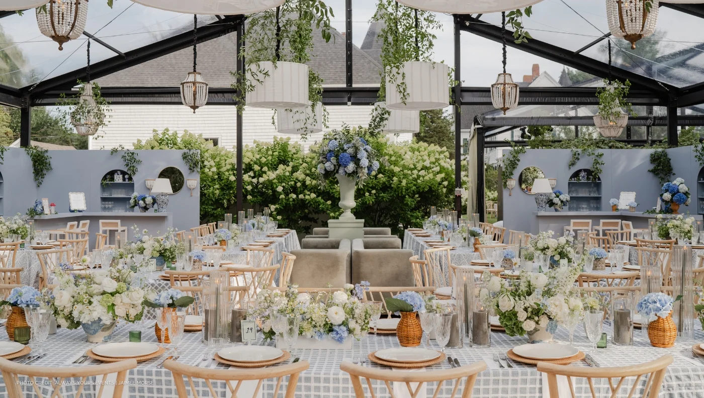 An elegant wedding reception set up in a glass tent with beautiful table linen rentals.