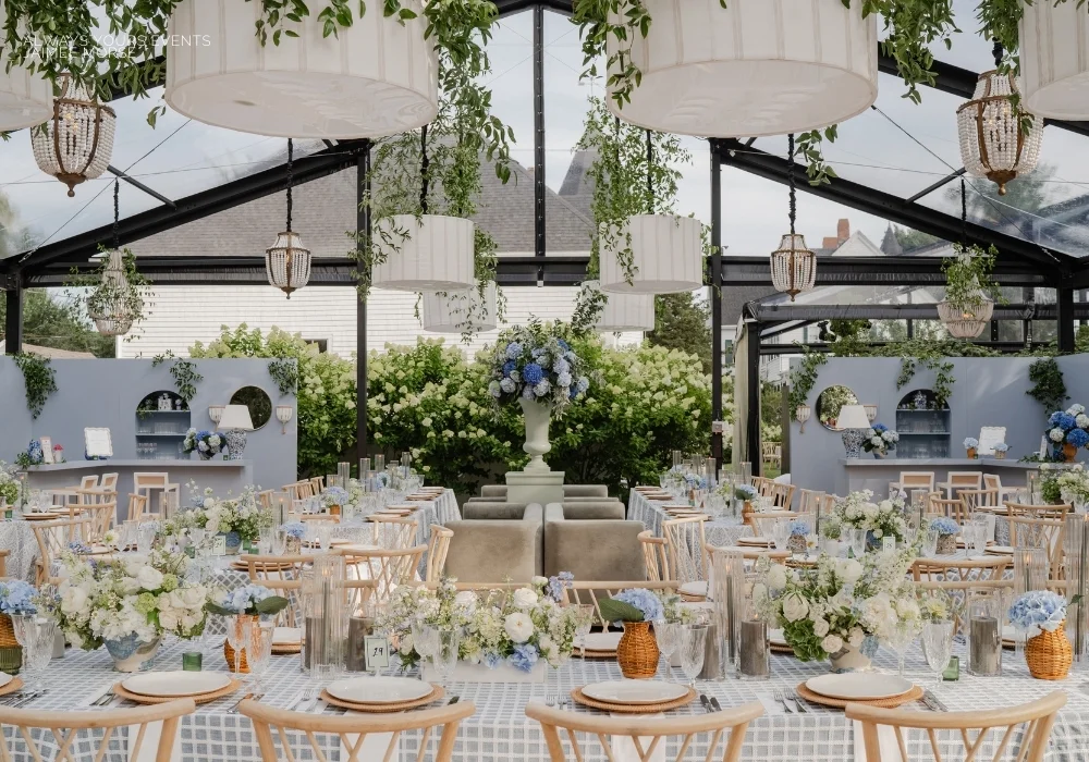 A stunning blue and white wedding reception set up in a glass tent, featuring elegant table linen rentals.