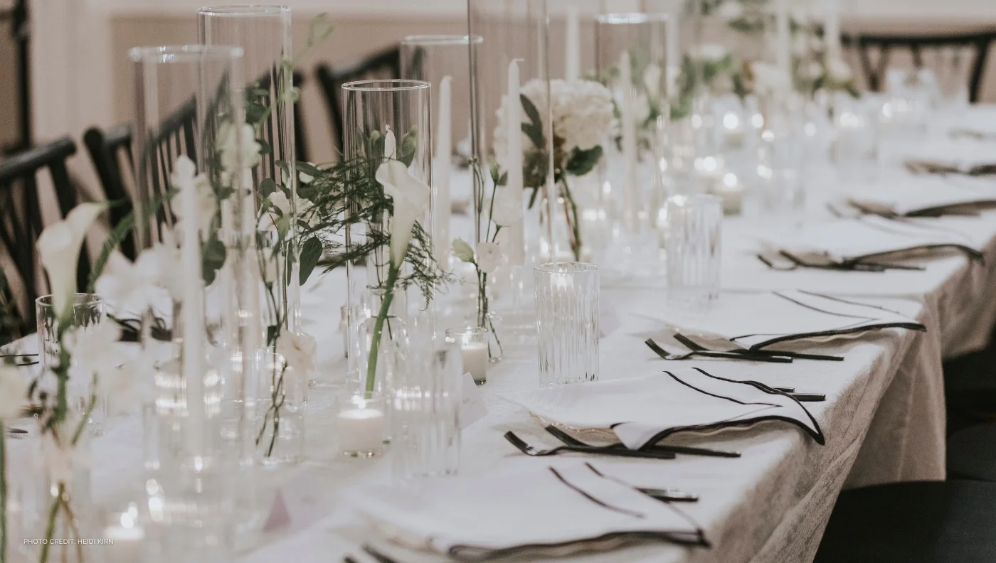 A long table set with white flowers and vases, decorated with elegant event linen rental.