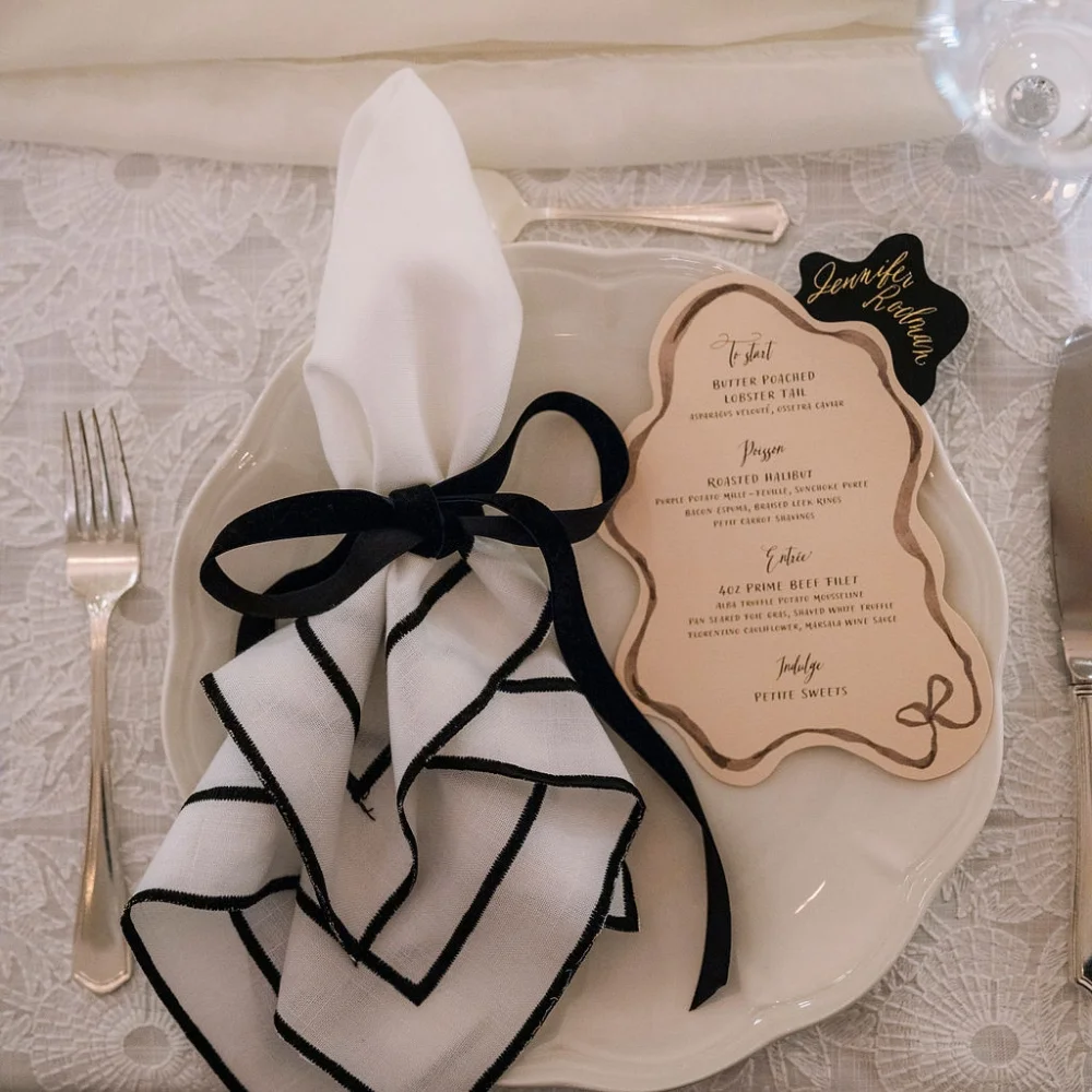 A black and white place setting with a napkin and fork.
