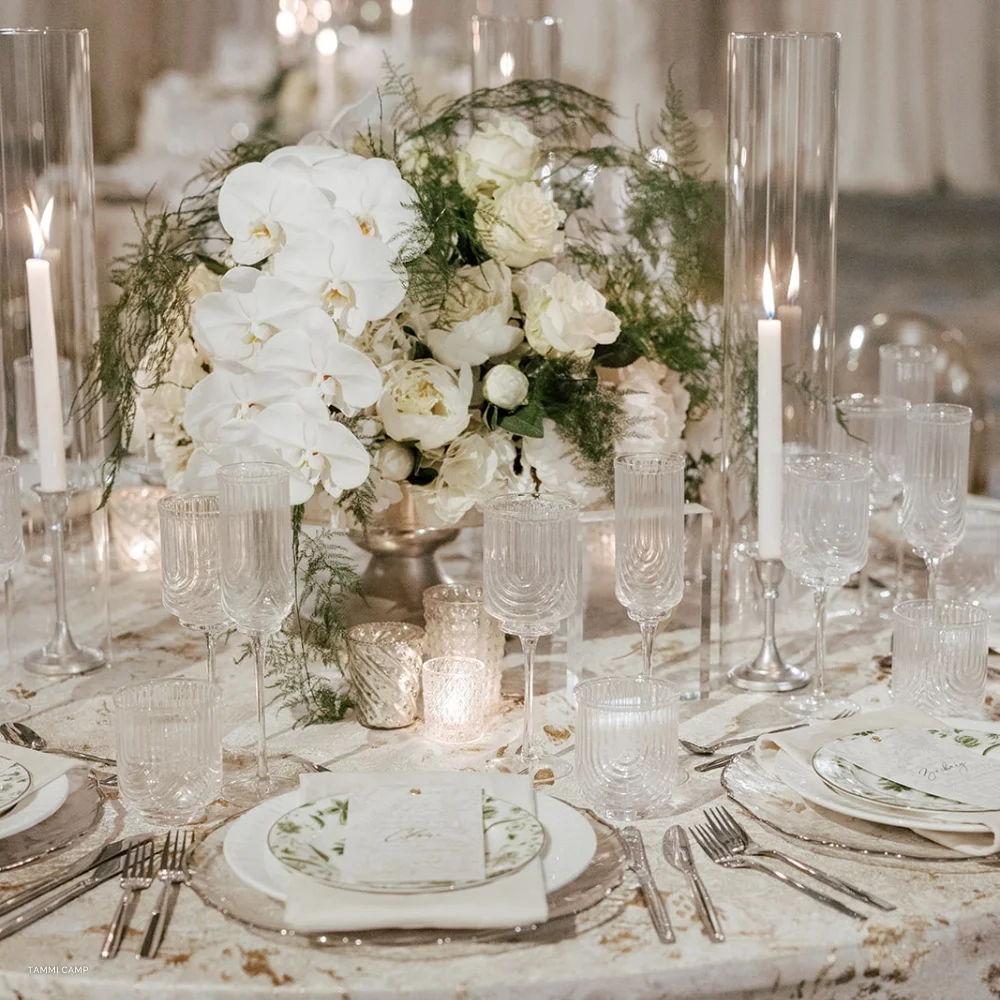 Elegant table setting at a reverie social event with white floral centerpieces and lit candles.