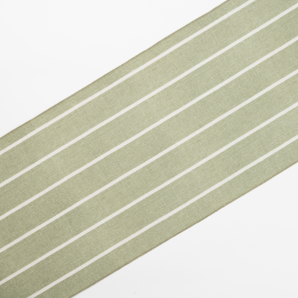 Diagonal view of the Madeline Aloe Table Runner showcasing its light green fabric with parallel white stripes.
