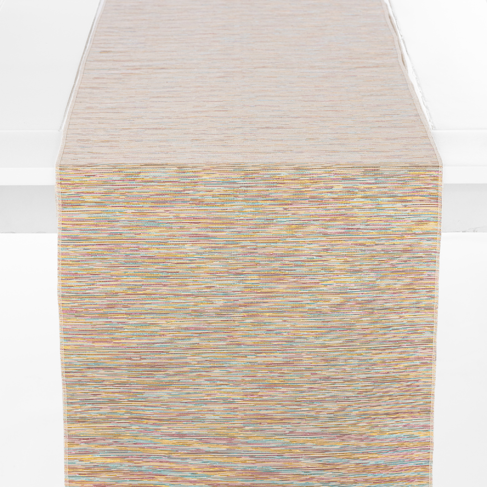 The Roxy Rainbow Metallic Table Runner is showcased on a white surface, displaying a multicolored, textured fabric with earthy-toned horizontal lines.